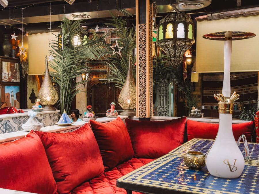 Red velvet cushions, a shisha pipe and colourful decorations at Oasis Lounge London, restaurants in North West London