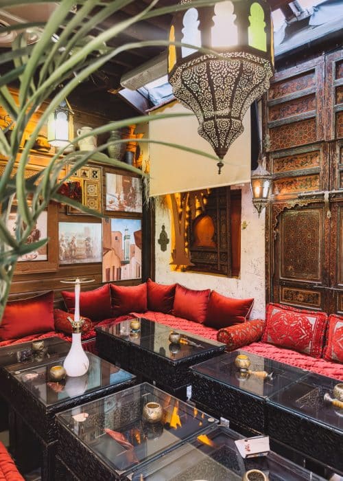 Vibrant red chairs, intricate lamps and plants at Oasis Lounge London, best Moroccan restaurants in North London