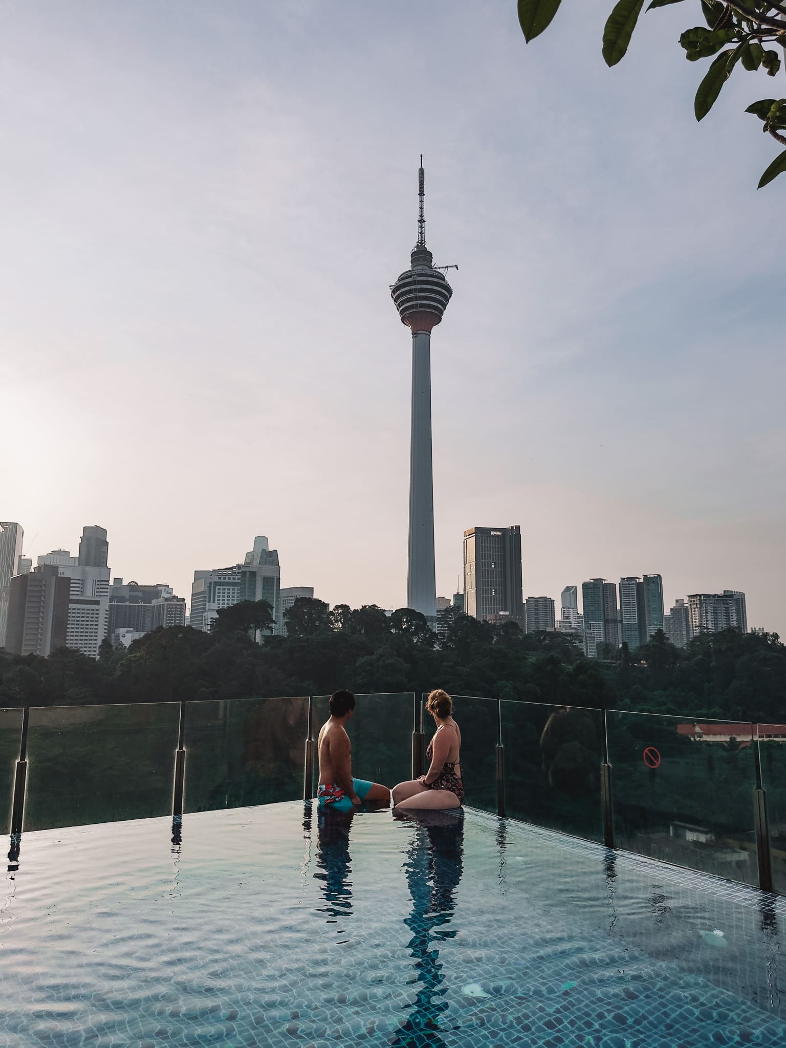 Helen and Andy sitting on the corner of the rooftop pool at Hotel Stripes looking at the KL Tower, where to stay in Kuala Lumpur