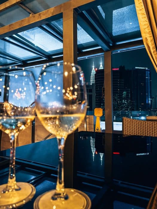 Two glasses of wine on the rooftop bar at Hotel Stripes with the Petronas Towers in the background, Hotel Stripes, where to Stay in Kuala Lumpur, Malaysia