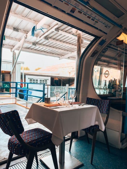 A disused 1967 Victoria Line tube carriage set up beautifully for a meal, Walthamstow Supperclub, London