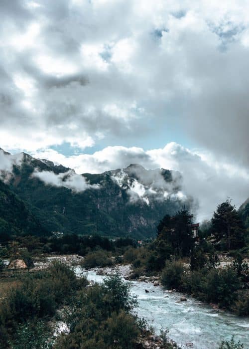 A turquoise gushing river flowing towards the mountains in Theth, Albania