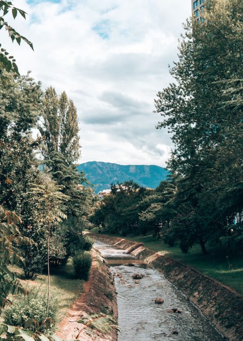 A river surrounded by trees with mountains in the background, things to do in Tirana, Albania