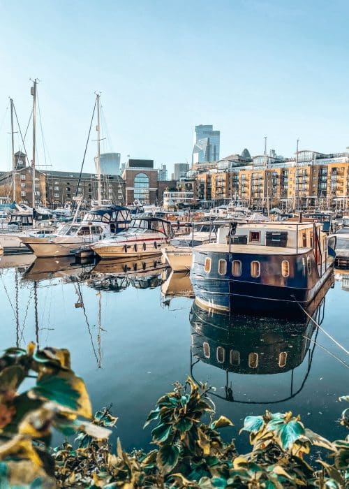 Boats on the water in front of historical buildings with skyscrapers behind, St Katharine Docks, London