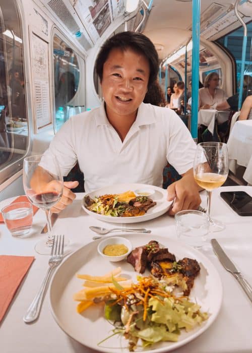 Andy sat on a disused vintage tube carriage having dinner at Walthamstow Supperclub, London