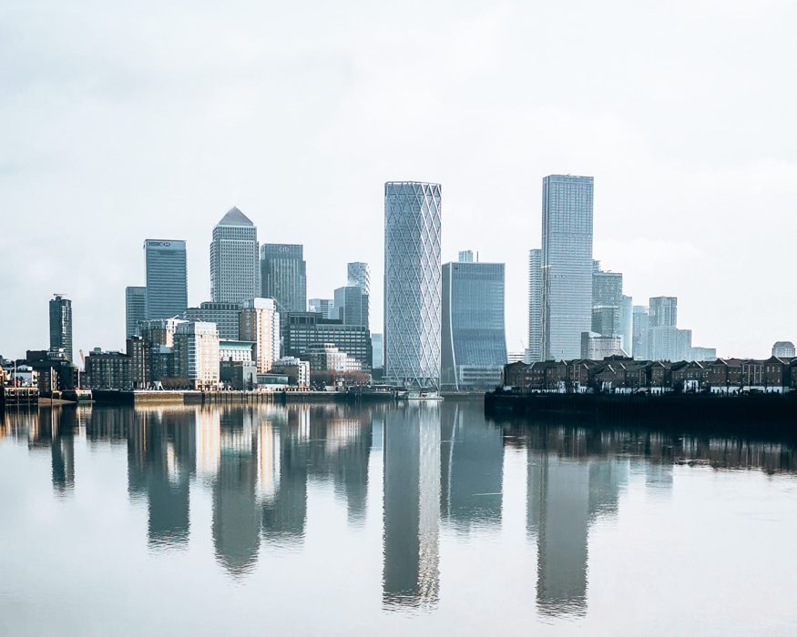 The view of Canary Wharf from The Thames Path on a still day with the reflection of the buildings in the water, London itinerary