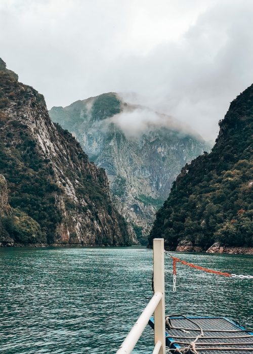 The Komani Lake Ferry sailing peacefully through towering jagged mountain peaks, Albania