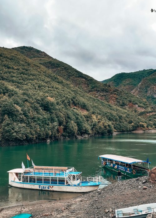 Two ferries sitting on Komani Lake surrounded by greenery, Shkoder to Valbona