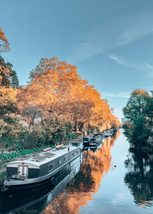 A barge sat on the peaceful water amongst trees on Hertford Union Canal, East London