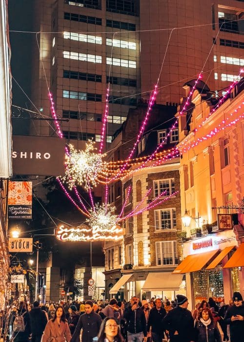Pink and gold sparkling lights strung between the buildings in Seven Dials, Covent Garden, Christmas lights in London
