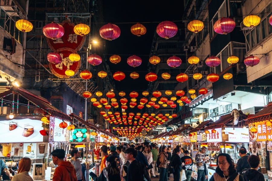 Colourful lanterns hang between buildings above hawker stalls at Temple Street Night Market, Best Things to do in Hong Kong