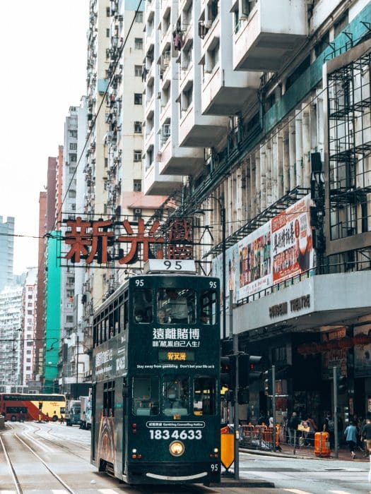 An old green tram riding through the streets on Hong Kong Island