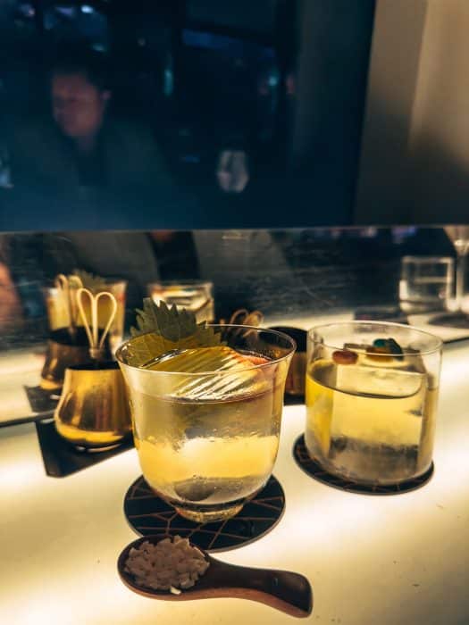 Two cocktails on the table in front of a window looking out across the skyline, things to do in Hong Kong