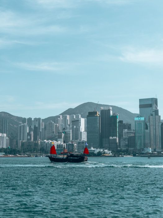 A traditional ship crossing Victoria Harbour in front of gleaming skyscrapers, Tsim Sha Tsui Waterfront, Kowloon, Hong Kong