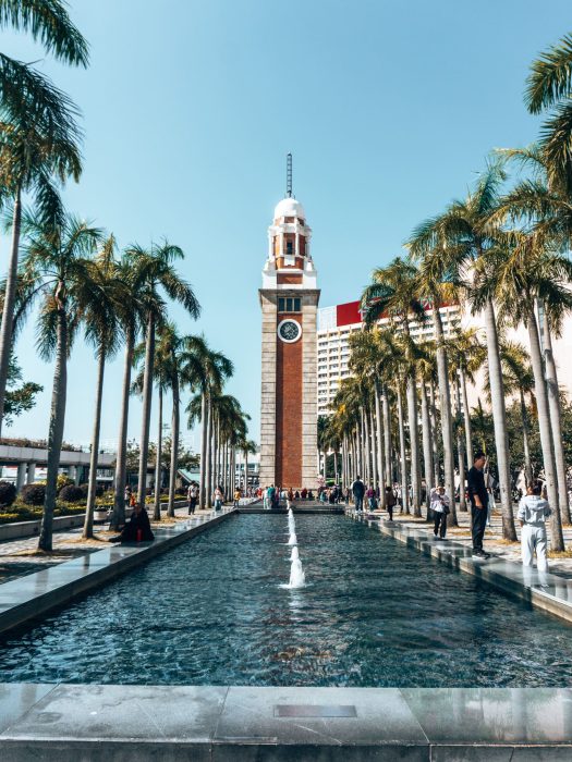 A clock tower at the end of a long water feature with palm trees, Former Kowloon-Canton Railway Clock Tower, Places in Hong Kong