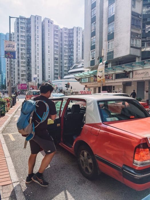 Andy getting into a red taxi on our Hong Kong Itinerary