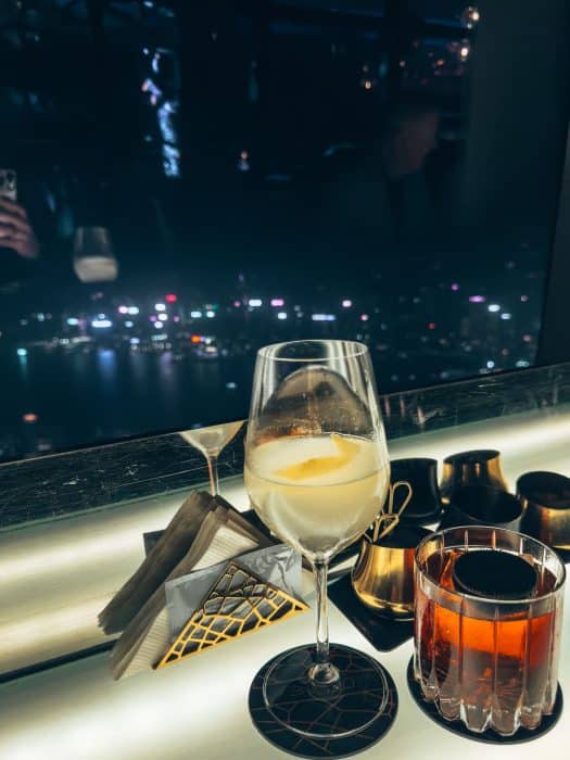 Two cocktails and a view from Ozone Bar over Kowloon and Hong Kong Island lit up at night