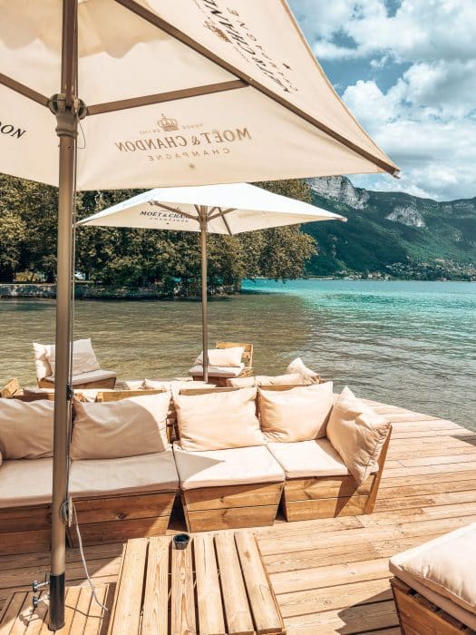 Chairs and parasols next to Lake Annecy at Le Pop Place