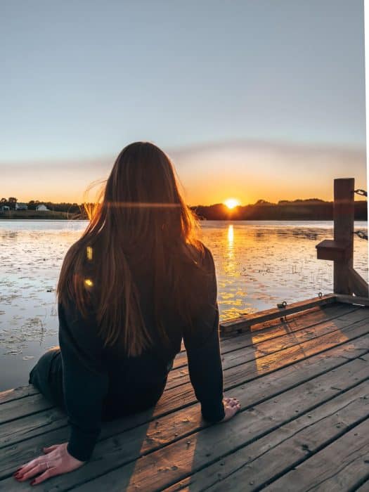 Helen sitting looking across a lake at sunset at Little Lake Family Campground, Lunenburg