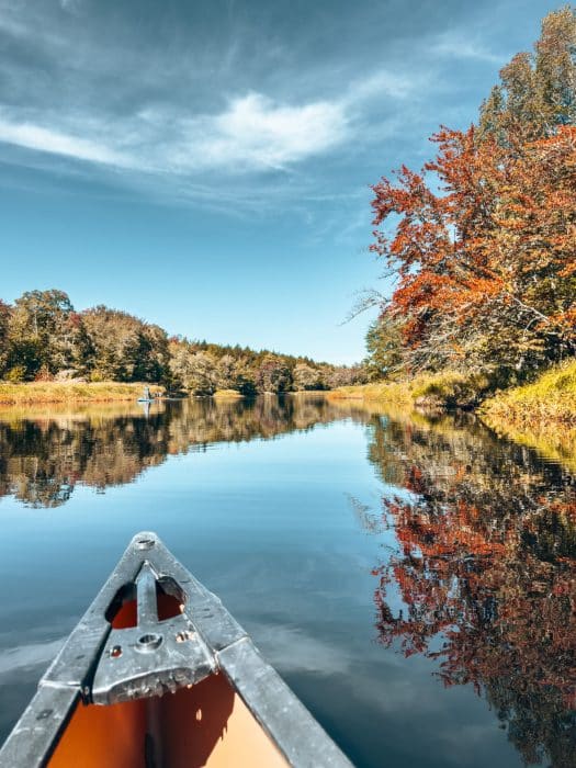A canoe in the peaceful waterway surrounded by autumn colours in Kejimkujik National Park, best things to do in Nova Scotia