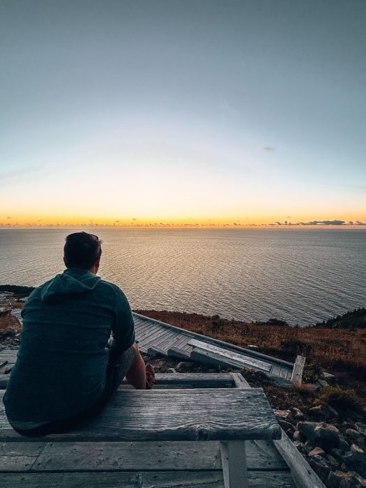 Andy sitting gazing out across the Atlantic Ocean at sunset on the Skyline Trail, Nova Scotia
