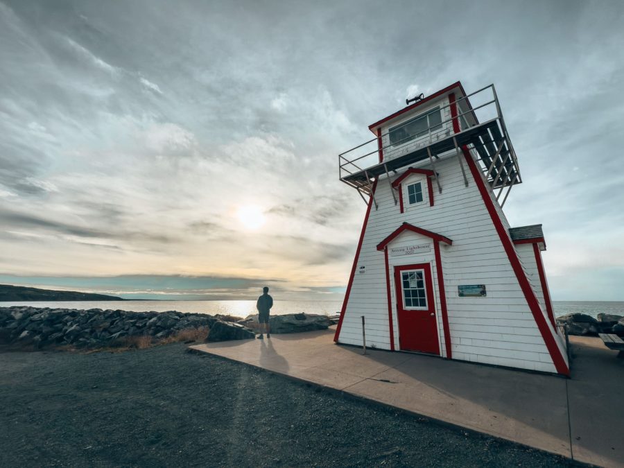 Andy stood next to the white and red Arisaig Lighthouse looking out to the ocean, best things to do in Nova Scotia