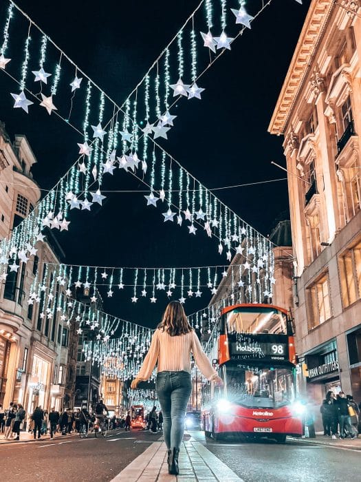 Helen stood in the middle of the road with hundreds of twinkling stars above her head on Oxford Street, London Christmas decorations
