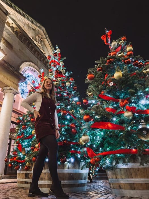 Helen stood in front of Christmas trees in Covent Garden at Christmas, best things to do in London at Christmas