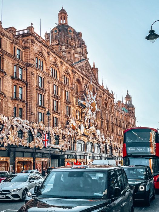 A red bus in front of Harrods golden exterior, London Christmas lights walking tour