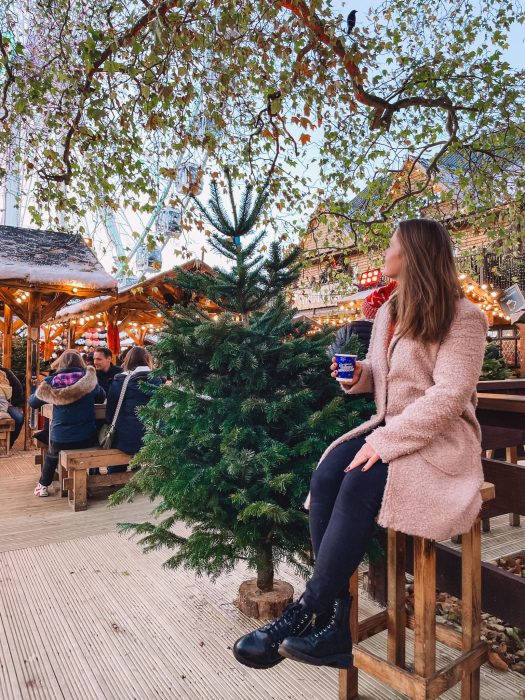 Helen sitting on a stool by a Christmas tree in Winter Wonderland, best things to do in London at Christmas time