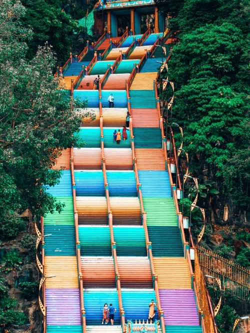 Tall multi-coloured stairs lined with green trees, Batu Caves, things to do in Kuala Lumpur, Malaysia